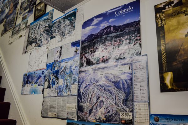 One wall in the shop is covered with trail maps from the mountains Exley has visited.