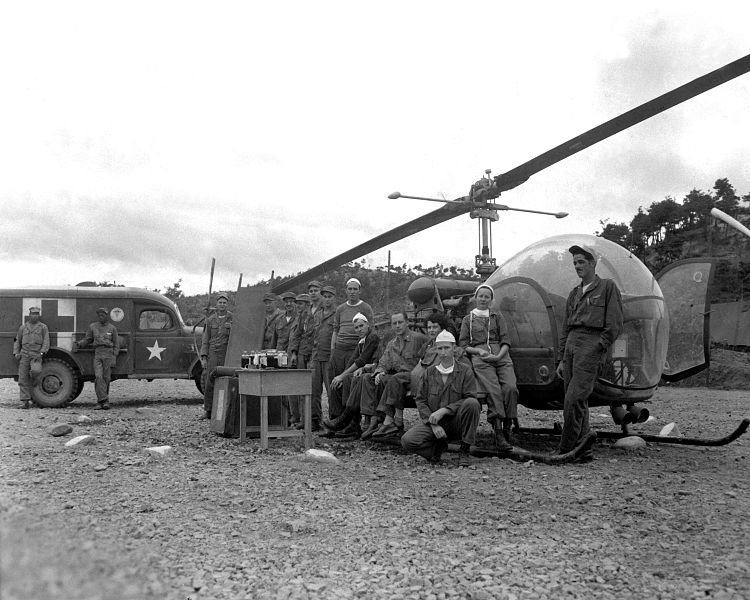 8225th MASH personnel posing with the type of helicopters they would use to evacuate wounded, 1951