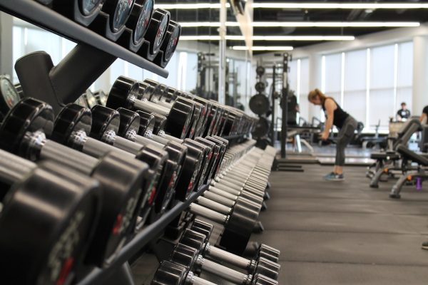 woman standing surrounded by exercise equipment new year's resolution