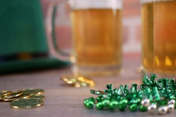 a table topped with two mugs of beer and gold coins st patricks day wheeling